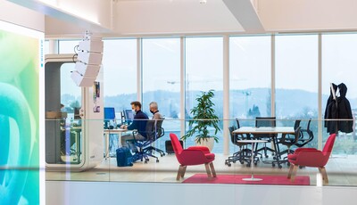 Intérieur d'un bâtiment moderne en verre avec du vitrage intelligent, des personnes travaillent à leurs bureaux.