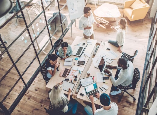 Groupe d'employés réunis autour d'une table dans un bureau lumineux entouré de vitrage intelligent.