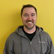 Headshot of a white man wearing a hoodie, in his 30's, against a yellow background.