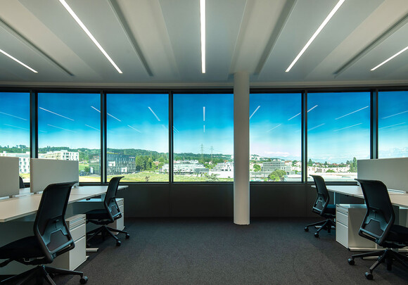 Espace de travail collaboratif avec des vitres intelligentes de gauche à droite donnant sur une ville. 