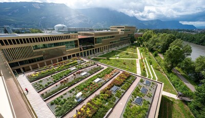 Extérieur du bâtiment situé derrière un espace vert. Le bâtiment est équipé de vitrage intelligent. 