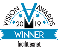 Logo avec texte bleu, noir et blanc indiquant « Vision V Awards Winner 2019 facilitiesnet »